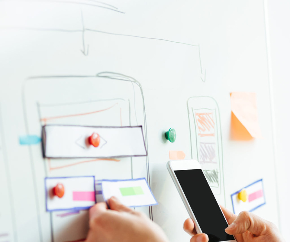 Application design mockups on a board with a mobile phone for reference